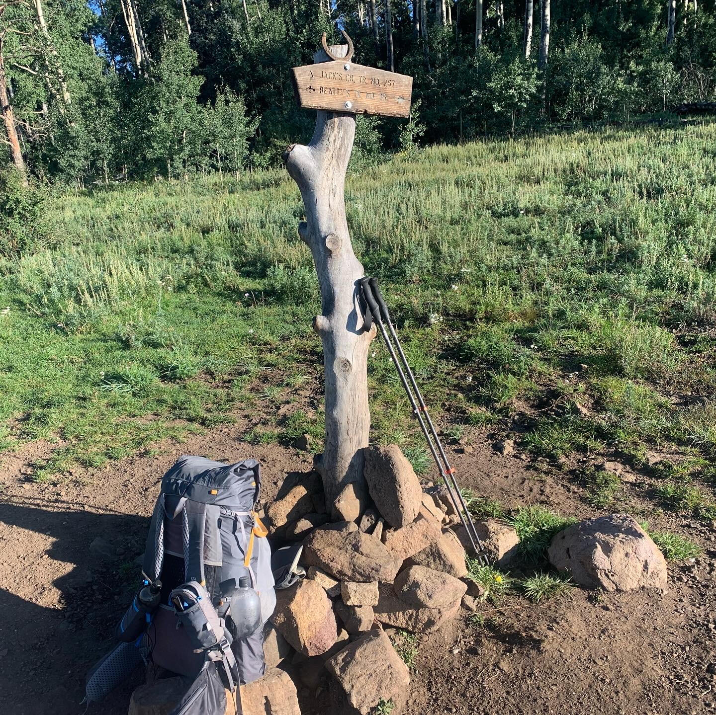 A lightweight backpack propped up on rocks at a trail intersection in the Rocky Mountains